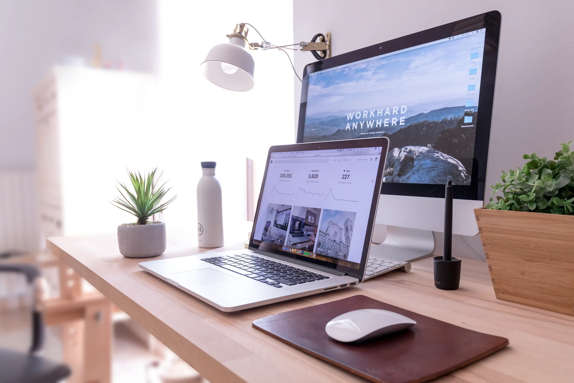 MacBook Pro setup on a clean desk showcasing the macOS Tahoe desktop
